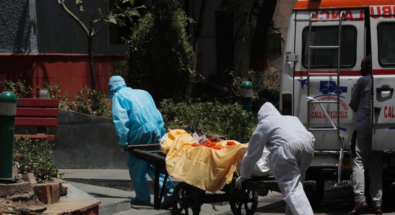 Health workers in personal protective suits ferry the body of a man who died of COVID-19 on a handcart for cremation in New Delhi, India, May 28, 2020.