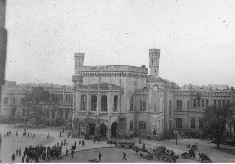 Dworzec kolejowy Wrocław Główny - widok zewnętrzny. Na placu przed dworcem widoczny tłum ludzi oraz kilka furmanek, 1945-1947 r.