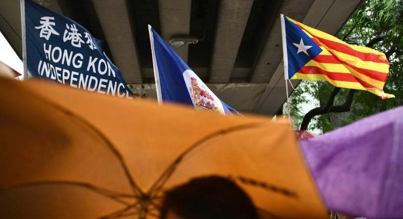 A flag that reads Hong Kong Independence is seen alongside the territory's British colonial-era flag and the pro-independence 'Estelada' Catalan flag during a march in Hong Kong on China's national day