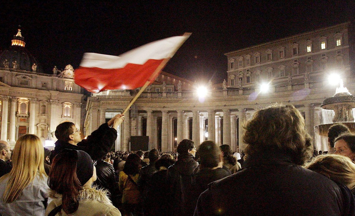 Jeden z pielgrzymów wznosi polską flagę narodową na Placu św. Piotra w Watykanie, 2 kwietnia 2005 roku wieczorem. Papież Jan Paweł II zmarł w sobotę, 2 bm. o godz. 21:37 - głosi komunikat Stolicy Apostolskiej