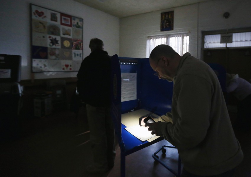 Leri Zasman glasa osvetljavajući listić mobilnim telefonom, jer na njegovom izbornom mestu u Oušensajdu u Njujorku i dalje nema struje