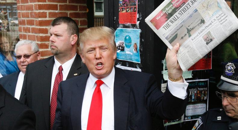 Donald Trump holds up a newspaper as he makes a reference to a story in it in 2011.