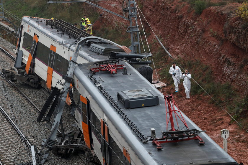 Firefighters, police and other officials survey the scene after a commuter train derailed between Te