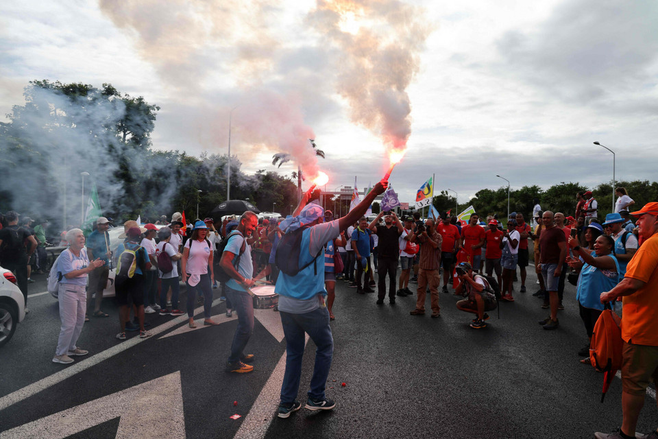 Mężczyzna pali race podczas protestu wzdłuż autostrady prowadzącej do lotniska w Sainte-Marie na francuskiej indyjskiej wyspie La Reunion, 7 marca 2023 r.