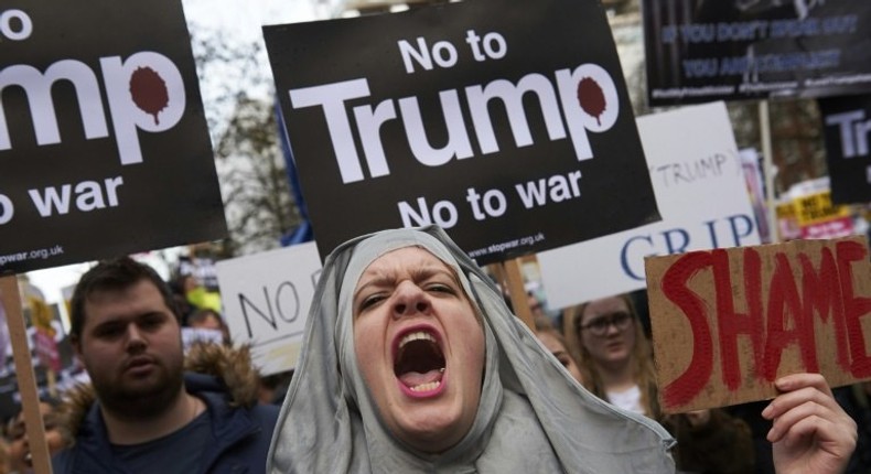 Demonstrators hold placards in protest against US President Donald Trump outside US Embassy in London on February 4, 2017