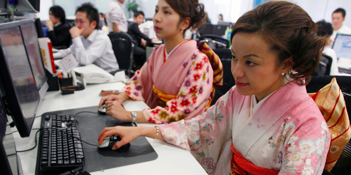 Employees of a foreign-currency brokerage firm dressed in traditional Japanese kimonos work in a dealing room.