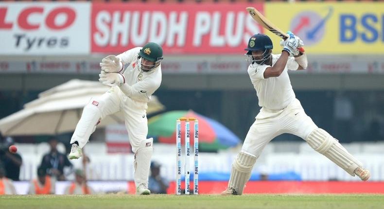 Indian batsman Cheteshwar Pujara plays a shot as Australian wicketkeeper Matthew Wade looks on on the fourth day of their third Test match, at The Jharkhand State Cricket Association (JSCA) Stadium Complex in Ranchi, on March 19, 2017