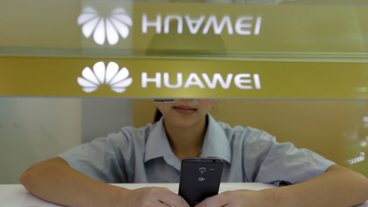 FILE PHOTO: A sales assistant looks at her mobile phone as she waits for customers behind a counter 