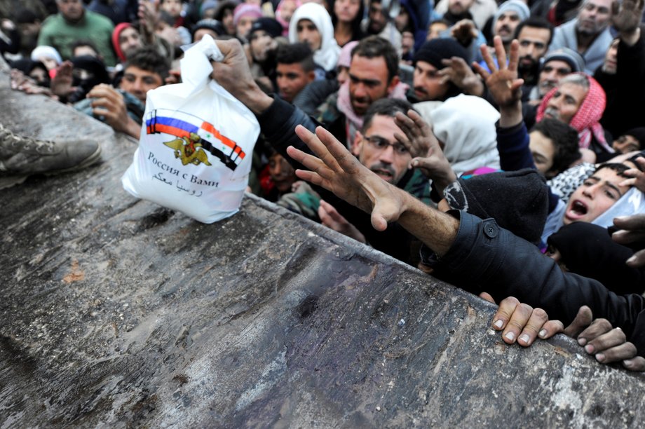 Syrians who have been evacuated from eastern Aleppo reaching out for Russian food aid in the government-controlled Jibreen area in Aleppo on November 30. The text on the bag, which shows the Syrian and Russian national flags, reads in Arabic: "Russia is with you."