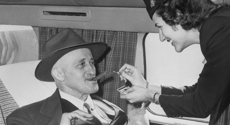 A flight attendant lights a passenger's cigar on a plane.Bettmann/Contributor/Getty Images