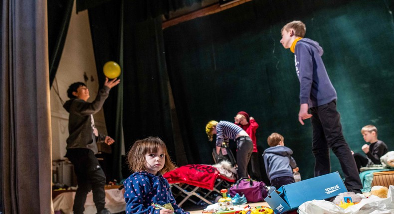 Children play on the stage of the theatre of the Ukrainian House where a shelter for refugees is installed in Przemysl, southeastern Poland, near the Ukrainian-Polish border, on March 18, 2022.