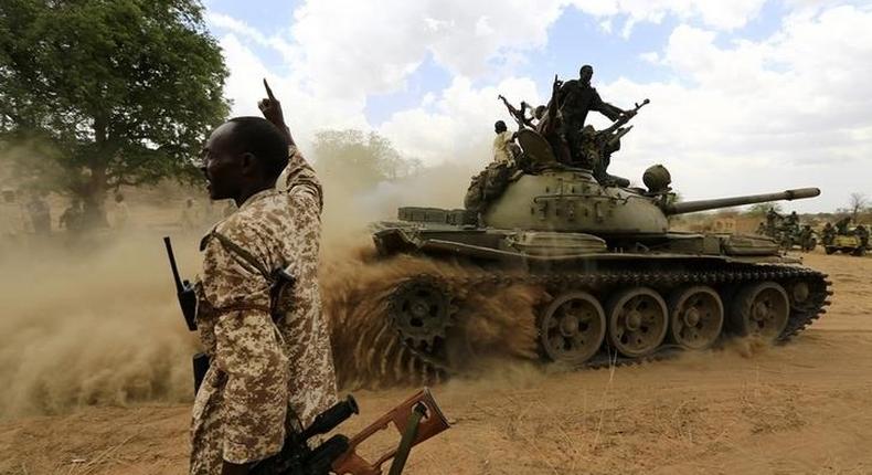 A military personnel gestures next to a tank after the Sudanese Armed Forces (SAF) and the Rapid Support Forces (RSF) recaptured the Daldako area, outside the military headquarters in Kadogli May 20, 2014. 