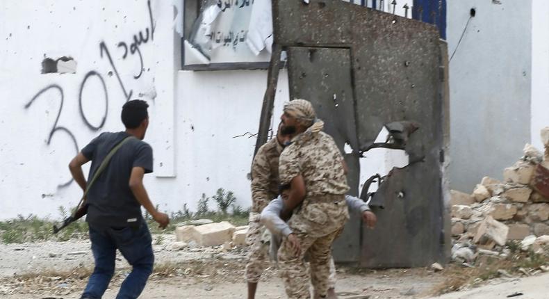 Fighters loyal to Libya's Government of National Accord carry a wounded man, as clashes rage south of the capital Tripoli