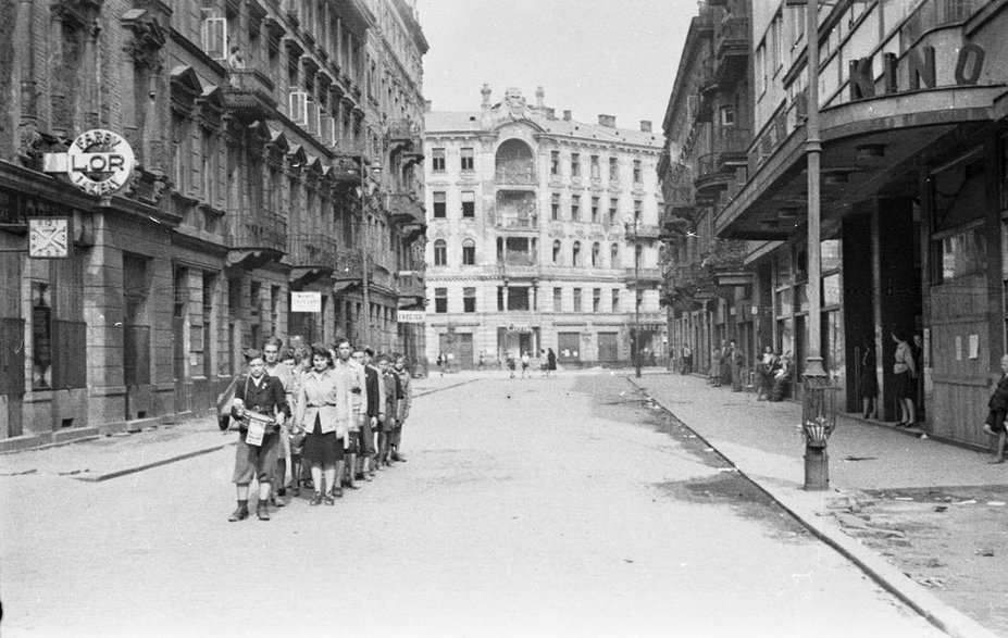 Grupa harcerzy na ulicy Złotej 7/9, po prawej widoczne wejście do kina Palladium