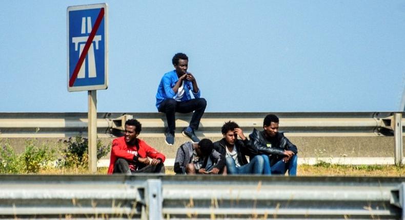 Migrants wait along the ring road leading to the port of Calais, northern France, in June 2017