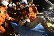 Rescue workers wearing face masks move a boy from the rubble of a collapsed hotel which has been used for medical observation following an outbreak of the novel coronavirus, in the southeast Chinese port city of Quanzhou, Fujian