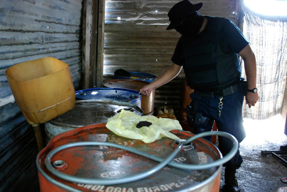 A policeman inspects barrels containing stolen diesel fuel, stored in a tire-repair shop, during an operation in the municipality of Apodaca near Monterrey, Mexico, July 4, 2011.