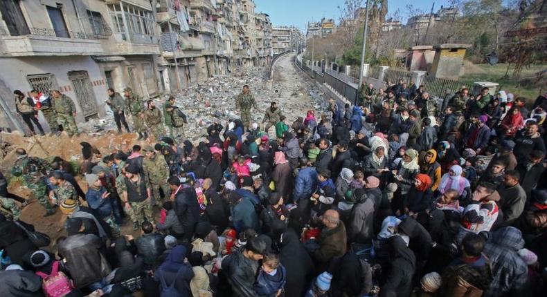 Syrian residents fleeing the violence gather at a checkpoint, manned by pro-government forces, in the Maysaloun neighbourhood of the northern embattled Syrian city of Aleppo on December 8, 2016