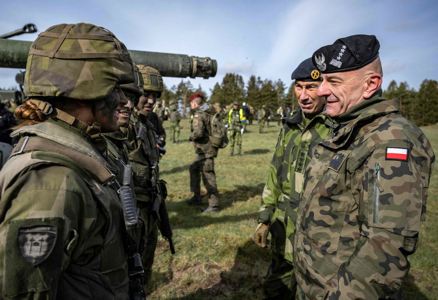 Najwyższy dowódca szwedzkiej armii Micael Byden (drugi po prawej) oraz Szef Sztabu Generalnego Wojska Polskiego Rajmund Andrzejczak (pierwszy po prawej) rozmawiają z załogami czołgów podczas ćwiczeń wojskowych Aurora 23 w Szwecji, 6 maja 2023 r.