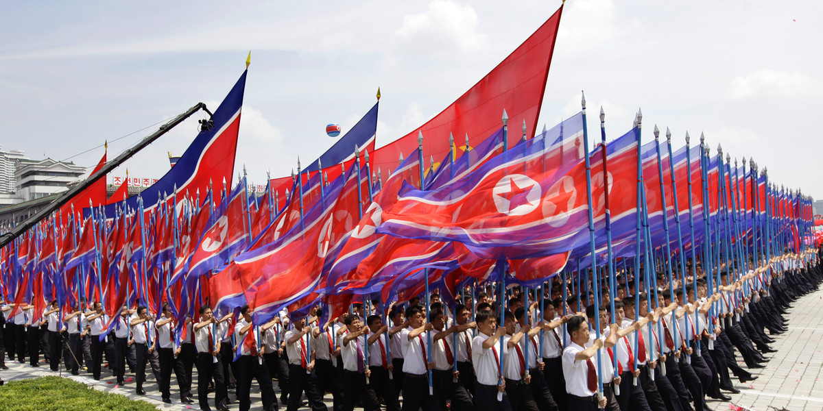 North Koreans holding national flags march during a parade to mark the 60th anniversary of the signing of a truce in the 1950-1953 Korean War at Kim Il-sung Square, in Pyongyang July 27, 2013.