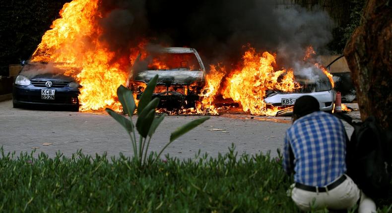 A photographer capturing images of cars burning after they were bombed at Dusit complex