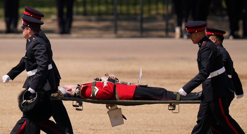 A British soldier is carried out on a stretcher after they fainted during a ceremony for Prince William on June 10.Associated Press