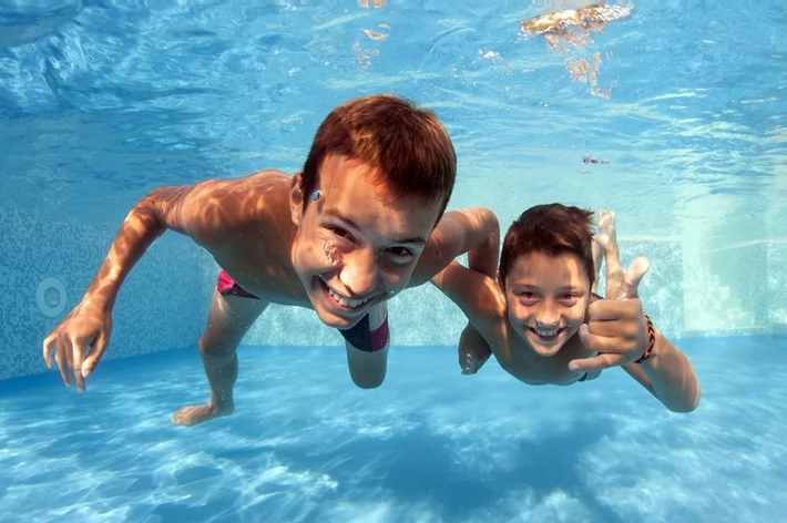 Underwater brothers portrait in swimming pool.