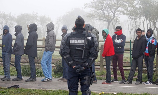 A French Gendarme stands near as migrants who claim to be minors wait for their registration and the