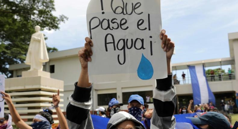 A student carries a sign reading Let the water pass during a protest of students and relatives of political prisoners, in Managua on Tuesday