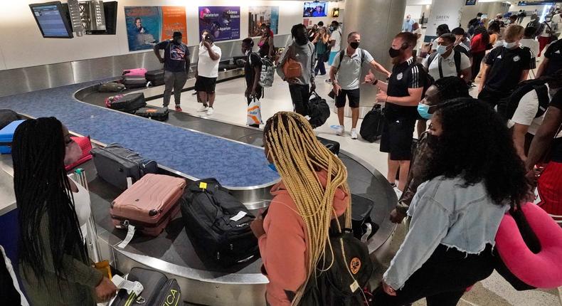Travelers wait for their luggage at a baggage carousel, Friday, May 28, 2021, at Miami International Airport in Miami.
