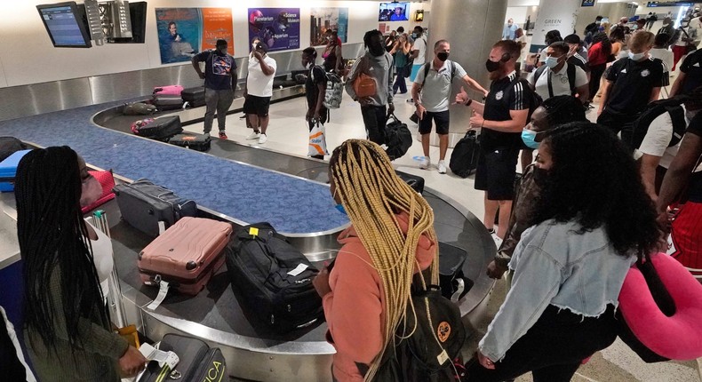 Travelers wait for their luggage at a baggage carousel, Friday, May 28, 2021, at Miami International Airport in Miami.
