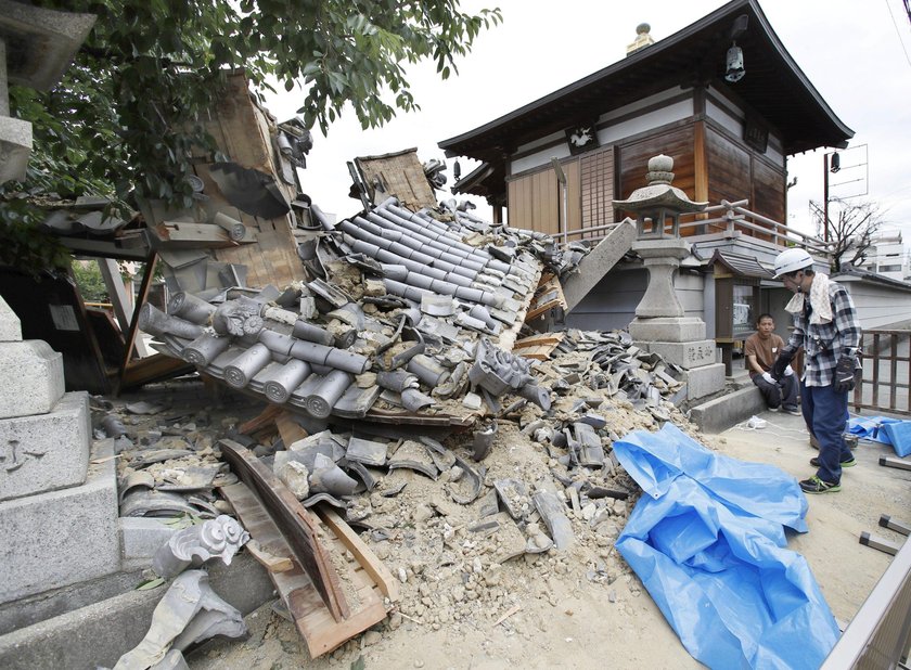 Employees try to remove bottles and cans of beverages which are scattered by an earthquake at a liqu