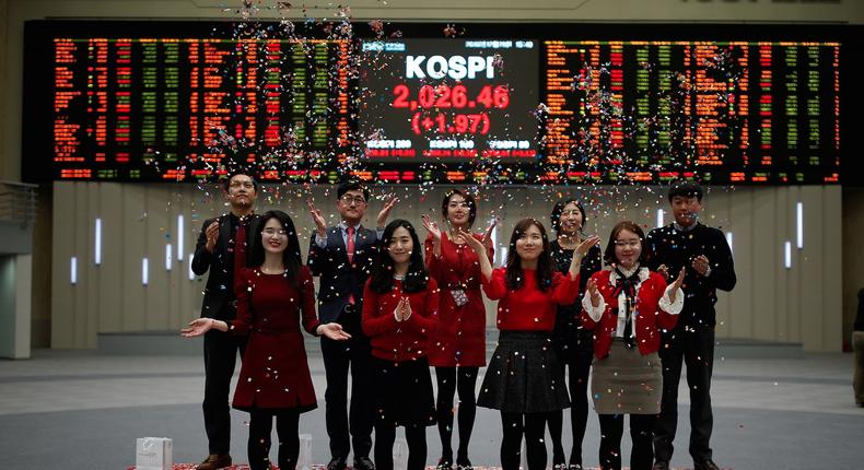 Employees of the Korea Exchange in front of the final stock-price index during a photo opportunity for the media at the ceremonial closing event of the 2016 stock market in Seoul, South Korea.