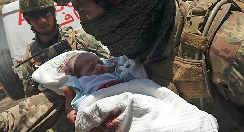 An Afghan security officer carries a newborn baby from a hospital after it is attacked in Kabul