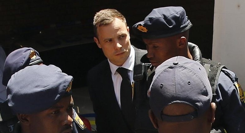 South African Olympic and Paralympic sprinter Oscar Pistorius (C) is escorted to a police van after his sentencing at the North Gauteng High Court in Pretoria October 21, 2014. REUTERS/Siphiwe Sibeko/Files