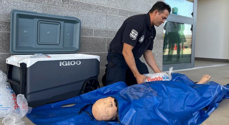 Phoenix Fire Captain John Prato demonstrates how emergency medical professionals can treat heat stroke with ice and a body bag.Anita Snow/AP Photo