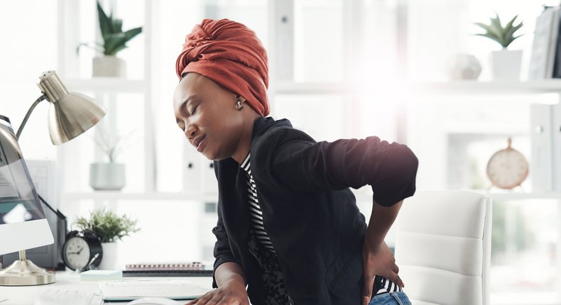 A woman experiencing back pain from sitting all day 