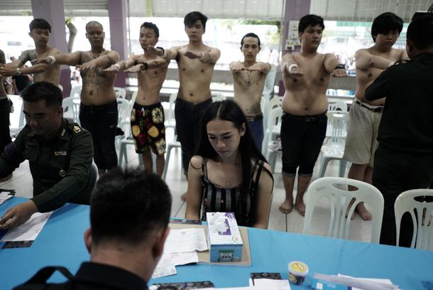 A transgender sits as she waits for her documents during an army draft held at a school in Klong Toe