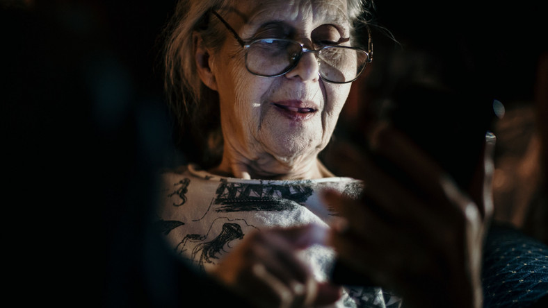 Starsza kobieta korzysta ze smartfona nocą
