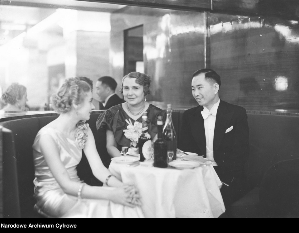 Grupa uczestników balu podczas rozmowy przy stoliku. Widoczni m.in.: sekretarz Poselstwa Japonii w Polsce How-Hsien Tang i pani Jadwiga Miklaszewska (w środku) w 1935 r.