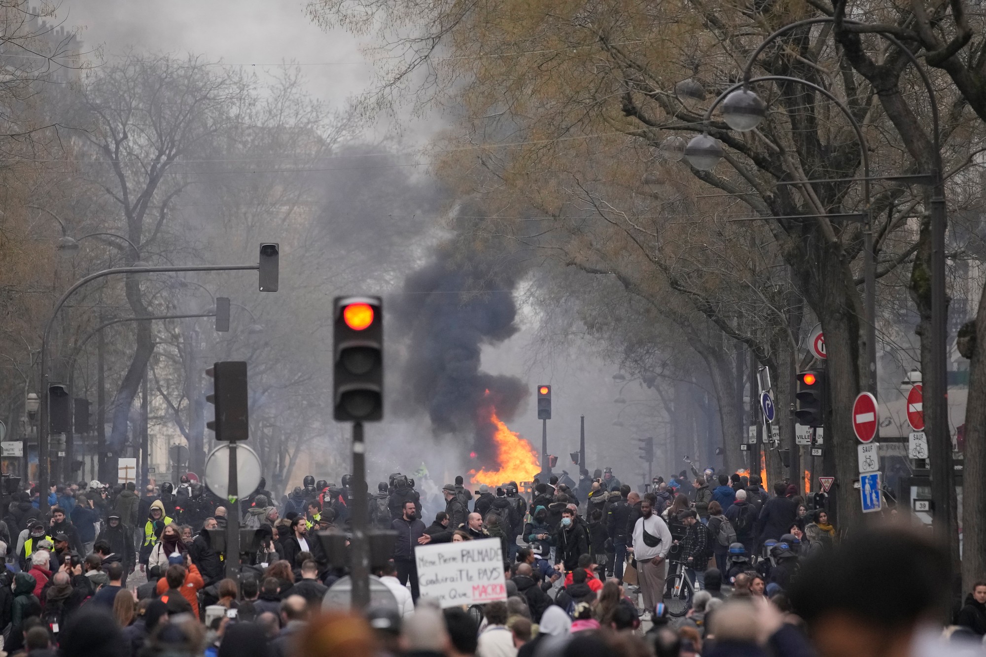 Demonštranti sa zhromažďujú pri horiacej barikáde počas pokračujúcich protestov proti nepopulárnej dôchodkovej reforme, ktorú presadil prezident Emmanuel Macron v Paríži vo štvrtok 23. marca 2023.