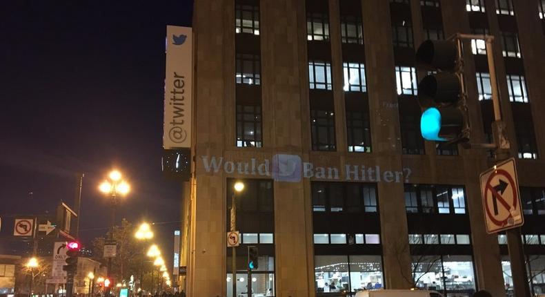 A projector displaying the message Would Twitter ban Hitler? on the side of Twitter's headquarters.