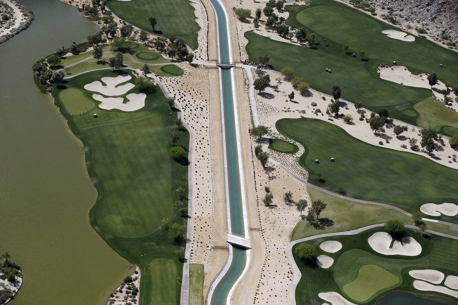 A dried-up canal runs through a lush green golf course in La Quinta.