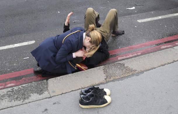 A woman assist an injured person after an incident on Westminster Bridge in London