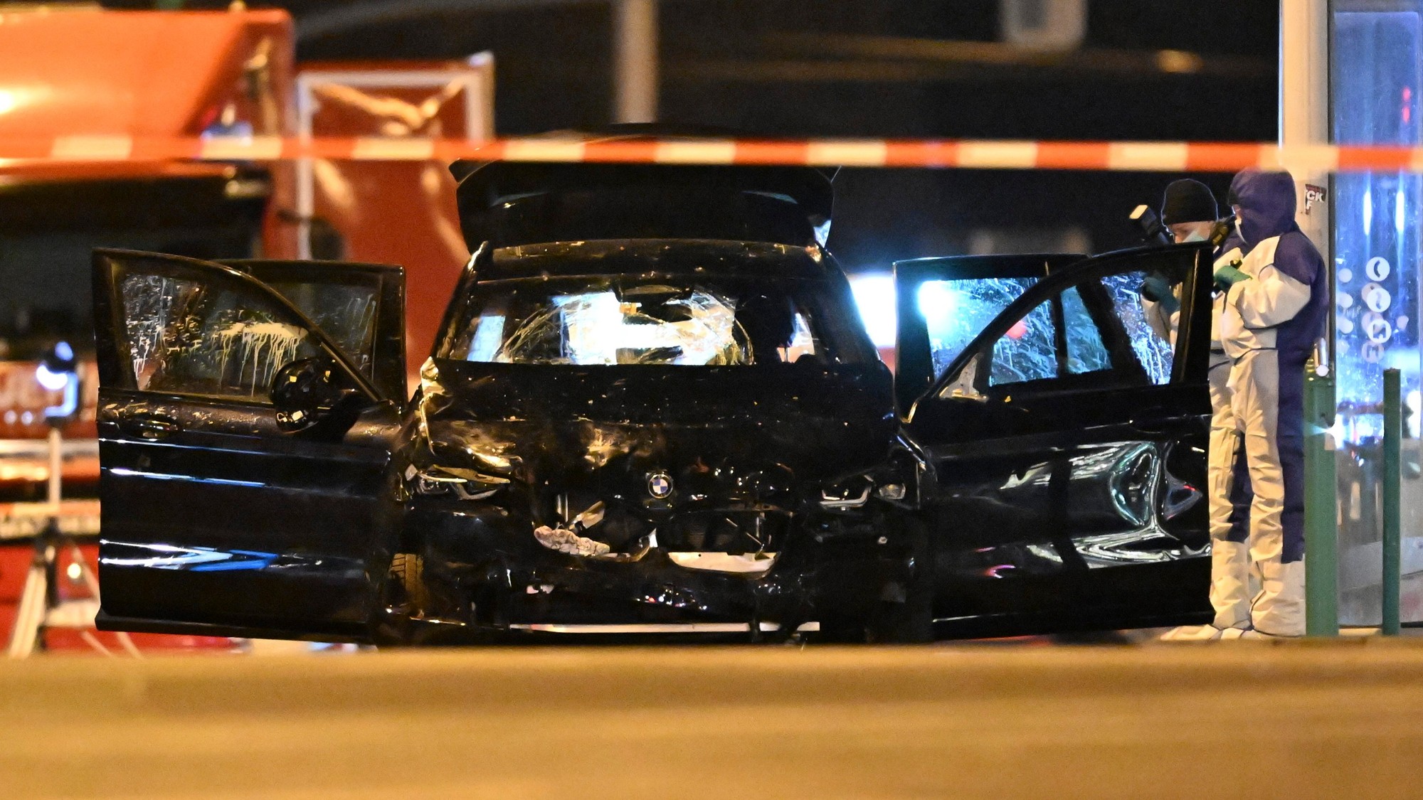 Kriminalisti pracujú na poškodenom aute s otvorenými dverami po tom, ako vodič vrazil do rušného vianočného trhu v Magdeburgu.