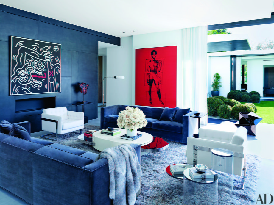 In the living room, walls of blackened-steel panels face off against a shag carpet and plush couches. The high-end artworks are by Keith Haring (left) and Andy Warhol (right). That piece in red is a portrait of artist Jean-Michel Basquiat.
