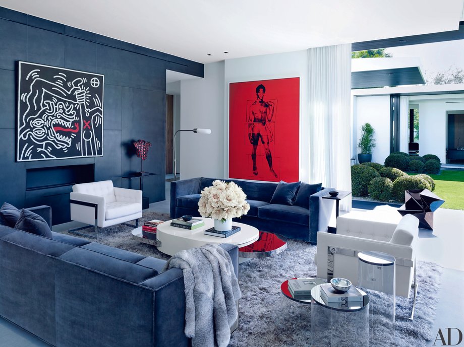 In the living room, walls of blackened-steel panels face off against a shag carpet and plush couches. The high-end artworks are by Keith Haring (left) and Andy Warhol (right). That piece in red is a portrait of artist Jean-Michel Basquiat.