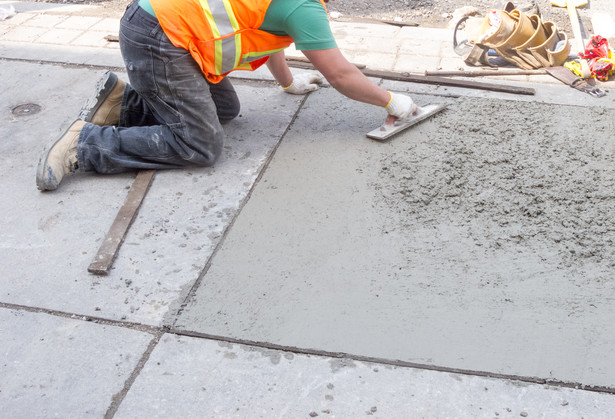 Budowlaniec wyrównujący beton na chodniku