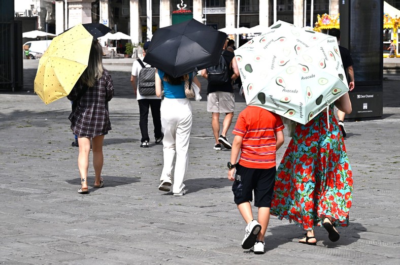 Piesi chronią się pod parasolami podczas fali upałów. Genua, Włochy, 17 lipca 2023 r.