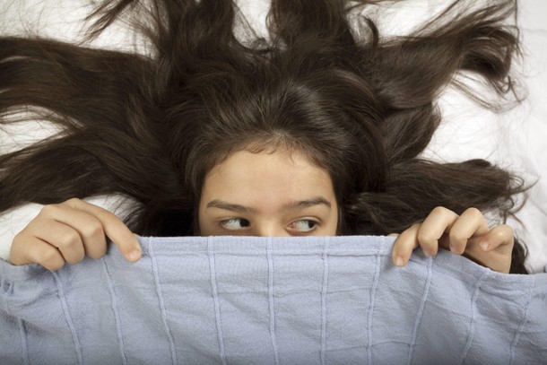 Scared girl hiding in bed